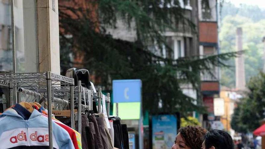 Dos vecinas miran prendas en un perchero de la Feria del Stock.