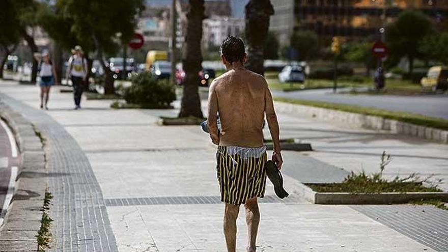 Un hombre pasea en bañador delante del antiguo edificio de Gesa en Palma.