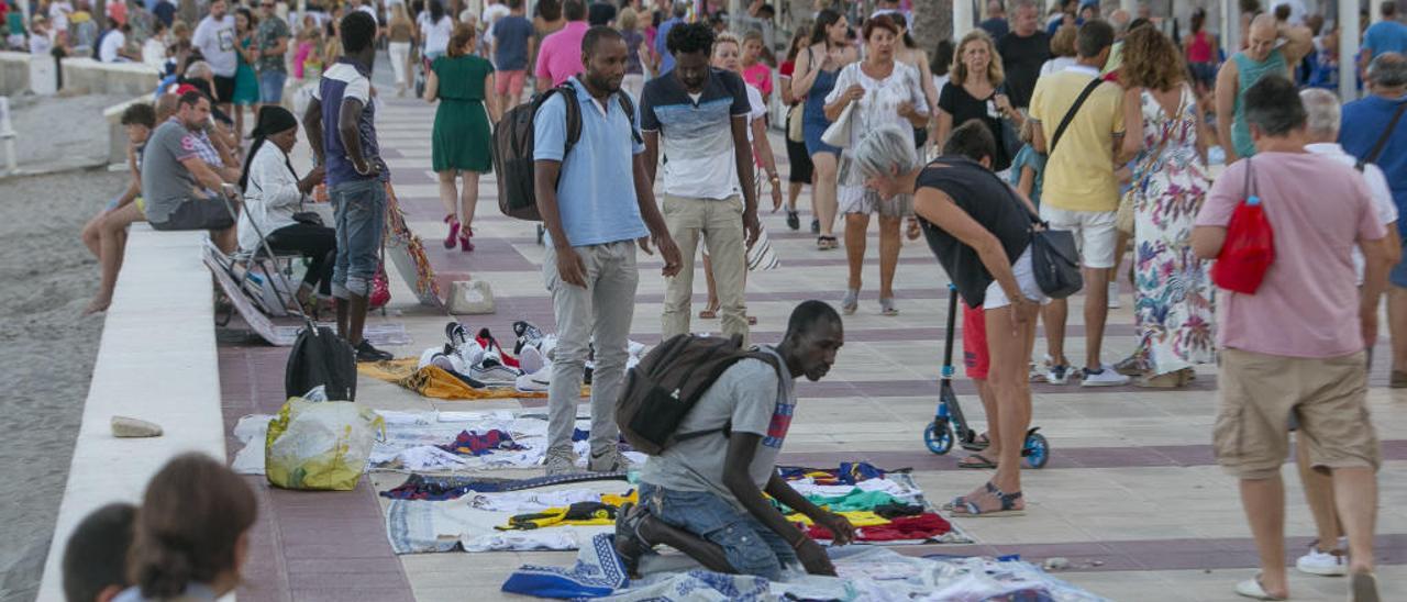 Vendedores del top manta un sábado de este verano vendiendo en el paseo marítimo de El Campello.