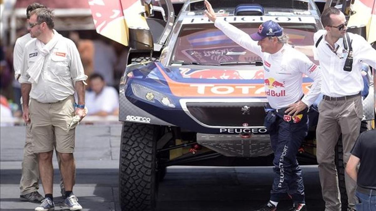 Carlos Sainz saluda al público antes de iniciar la etapa prólogo donde acabó segundo con su Peugeot