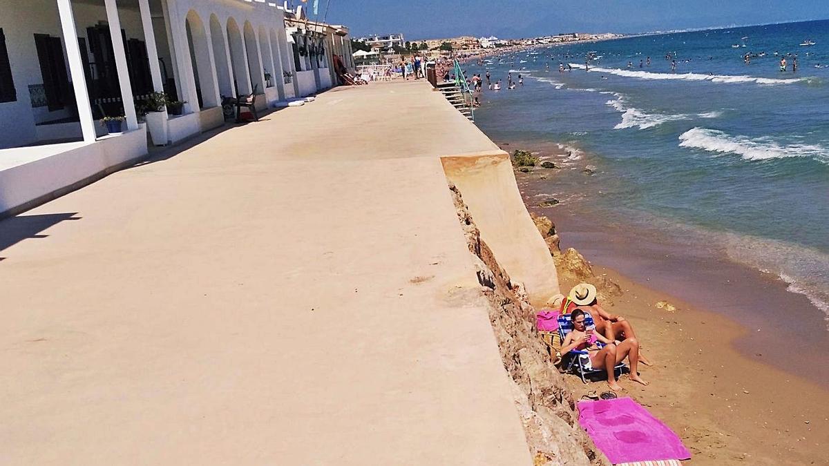 Bañistas que ayer disfrutaban de la playa en un pequeño hueco que mantiene arena. | A. P. F.