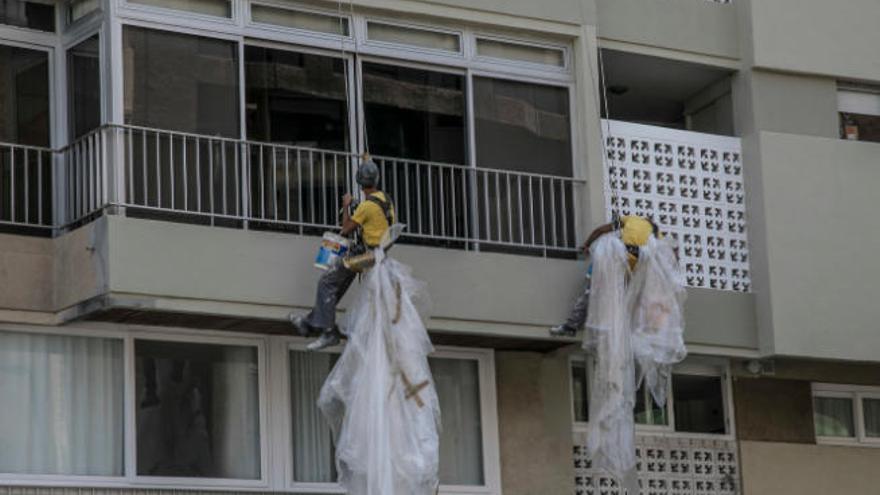 Los salarios no mejoran en las Islas. En la imagen, dos obreros trabajan pintando la fachada de un edificio.