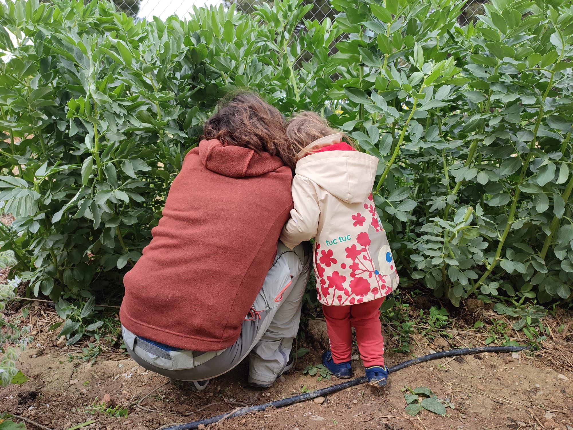 Una madre y su hija, en un rincón del huerto urbano.