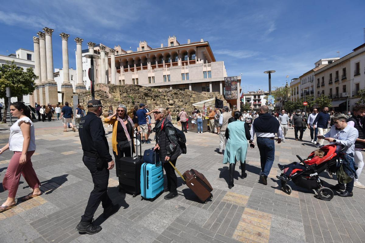 Unas turistas hablan con un Policía Local con el Ayuntamiento de Córdoba al fondo.
