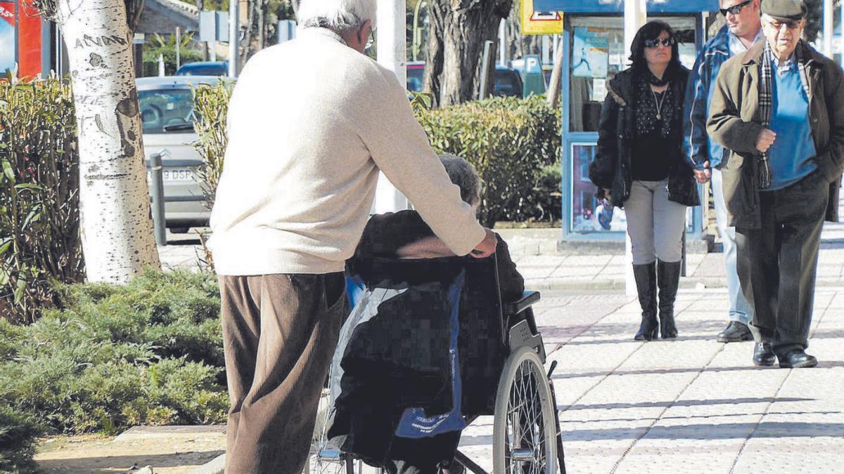 Un hombre pasea a una mujer en silla de ruedas.