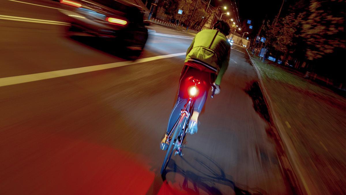 Un ciclista circulando por la carretera de noche.