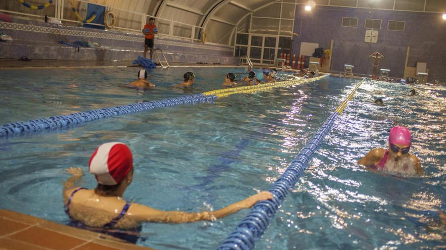 Nadadores y cursillistas en la piscina climatizada.