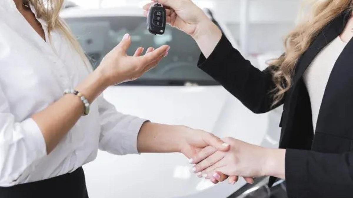 Dos personas cierran la venta de un coche.