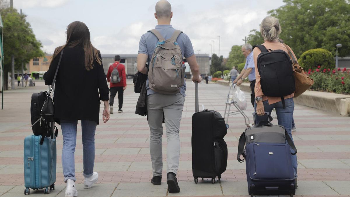 Varios turistas, maletas en mano, caminan por el Vial de Córdoba rumbo a la estación de trenes.