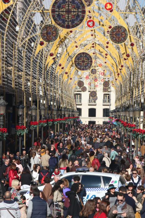 Muchos malagueños y turistas aprovechan el buen tiempo y el día festivo por la Inmaculada Concepción para pasear y realizar las compras navideñas en el Centro de Málaga.