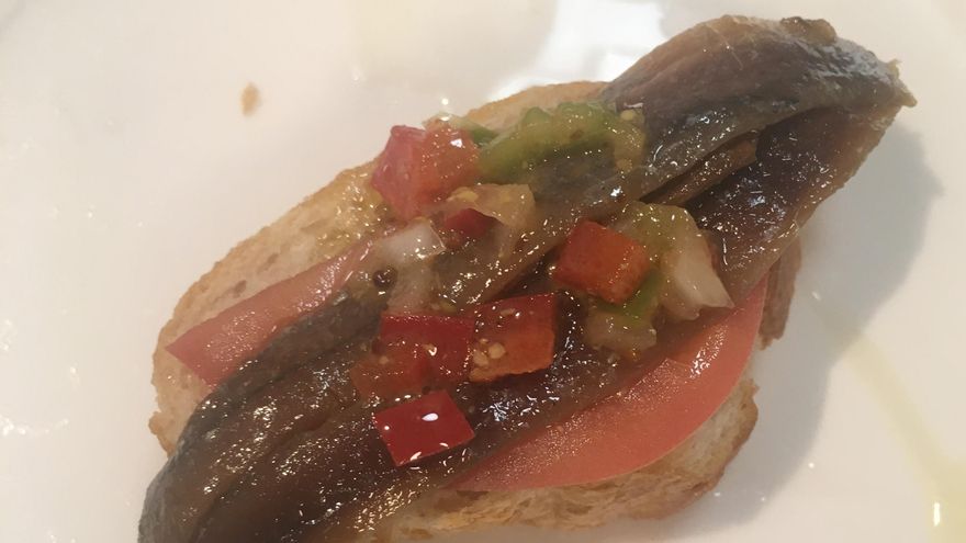 Anchoas sobre cama de tomate y vinagreta de pimiento y cebolla.