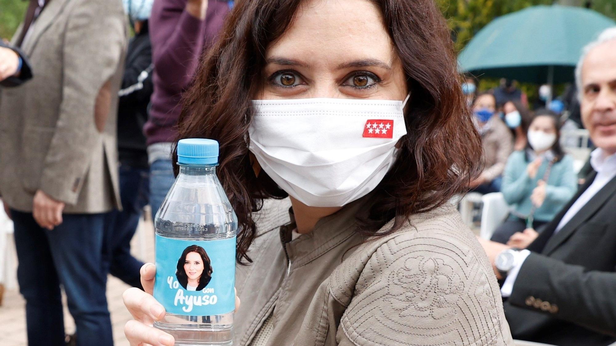 Isabel Díaz Ayuso posa con una botella de agua con su cara impresa durante un acto de campaña celebrado en Pozuelo de Alarcón