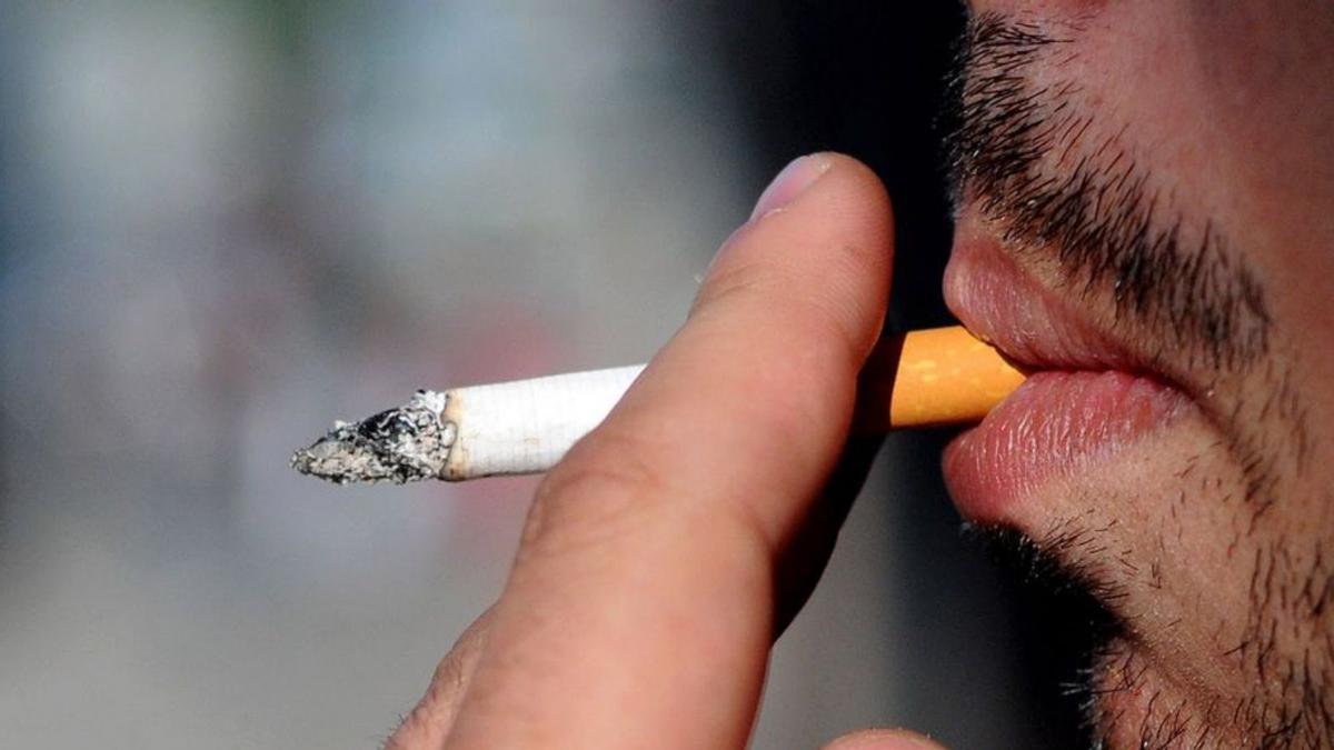 Un hombre fuma un cigarrillo.
