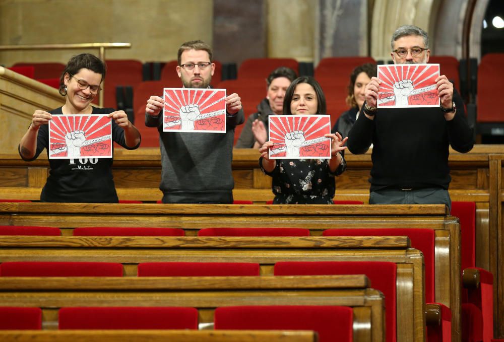 Diputados de la CUP sostienen sus pancartas de protesta dentro del edificio parlamentario.