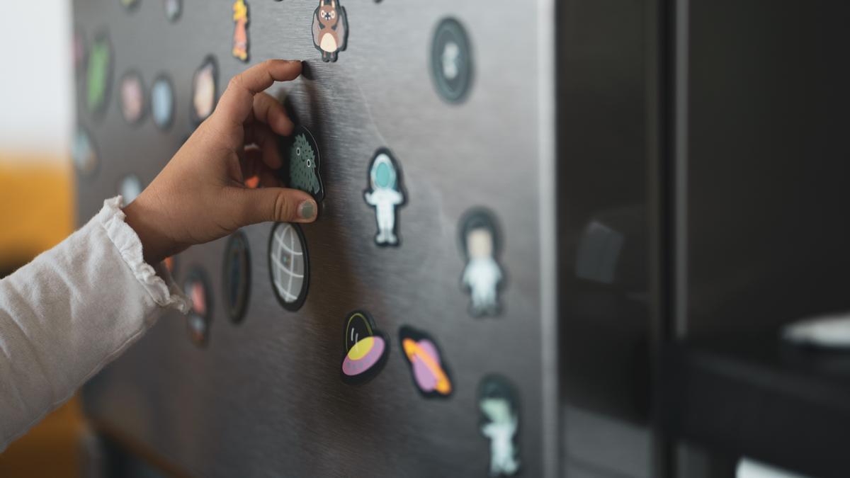 Un niño mueve imanes colocados en la puerta de un frigorífico