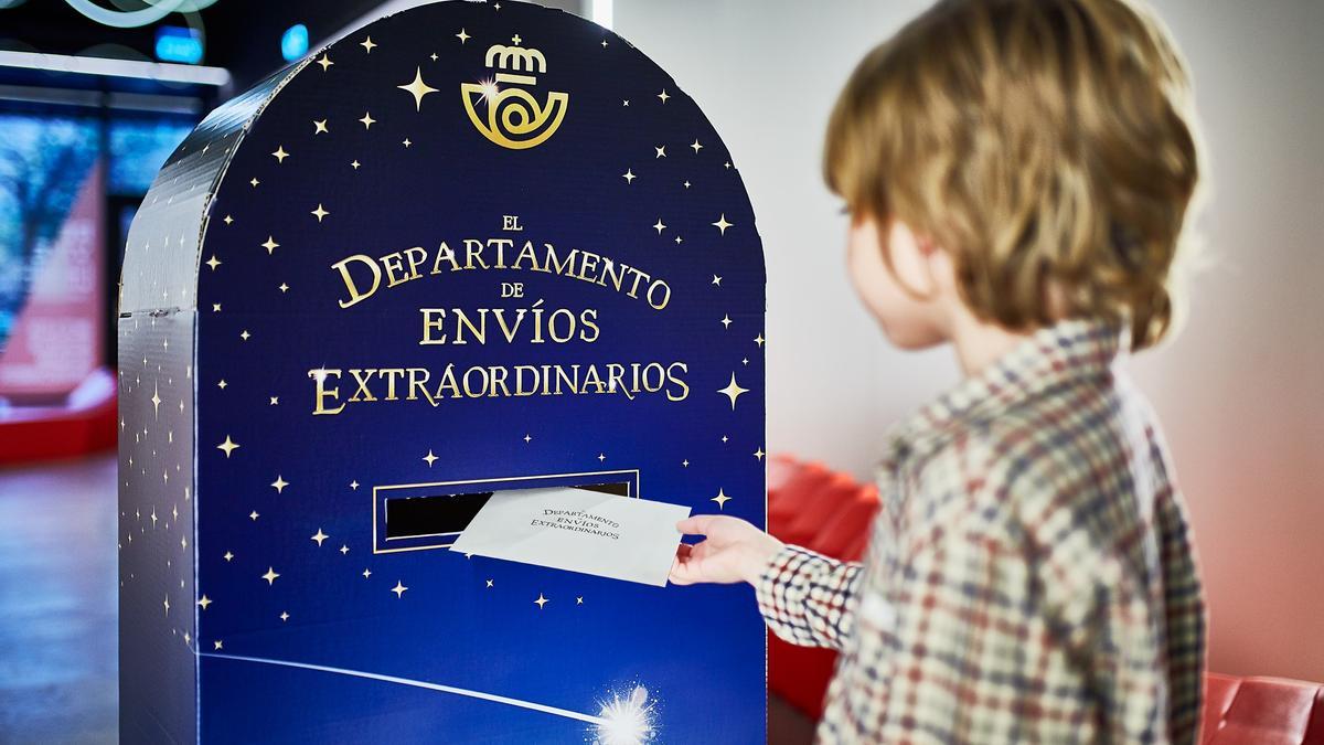 Un niño deposita su carta a los Reyes Magos en un buzón de Correos.