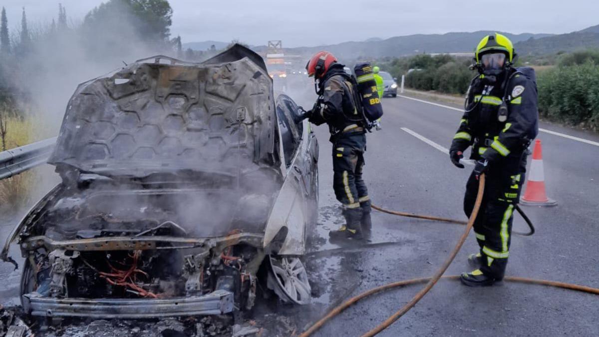 Los bomberos sofocando las llamas en el vehículo.