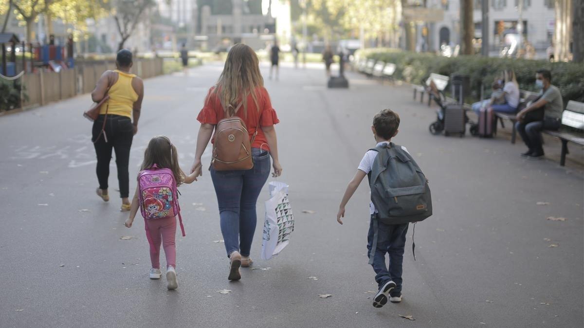 Una madre y sus dos hijos, camino de la escuela en el primer día de clase.