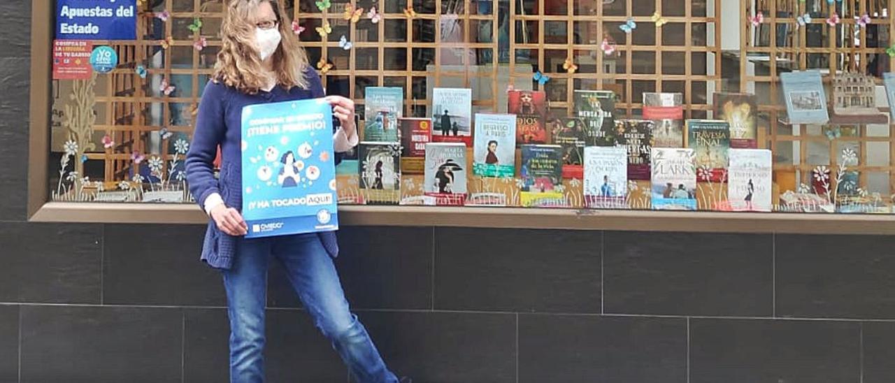 María Díaz de las Heras, con un cartel de la campaña, junto al escaparate de su librería de San Pedro Mestallón. | LNE