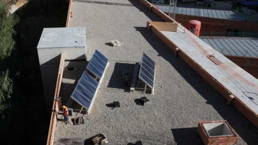 Operarios colocando placas solares en la cubierta del edificio.