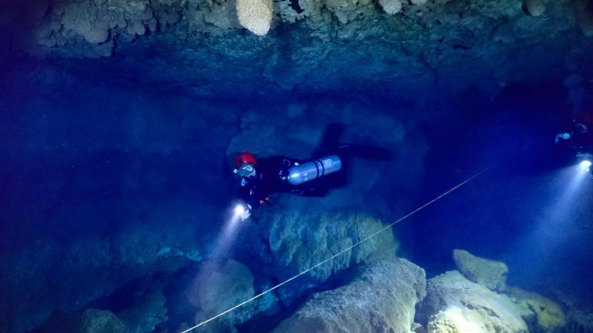 Un buceador de la Guardia Civil inspecciona el interior de una cueva acuática.
