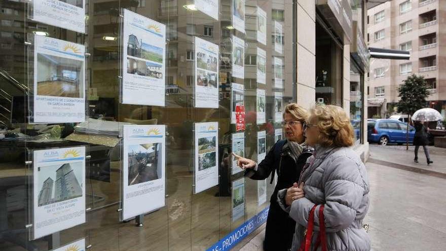 Transeúntes consultan los anuncios de una inmobiliaria en el centro de Vigo. // Alba Villar