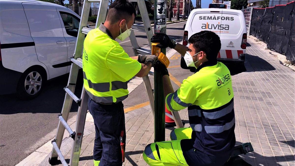 Operarios cambian la botonera de un semáforo en la carretera N-II en Mataró.