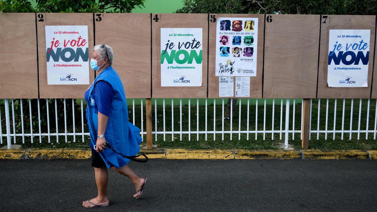 A woman walks past electoral boards near a polling station ahead of the referendum on independence in Noumea, on the French South Pacific territory of New Caledonia, on December 10, 2021. - The Pacific territory of New Caledonia goes to the polls on December 12 for a third and final referendum on independence from France with campaigning marked by angry demands to call off the vote because of the Covid pandemic. (Photo by Theo Rouby / AFP)