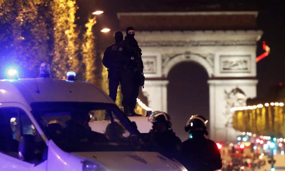 Masked police stand on top of their vehicle on ...