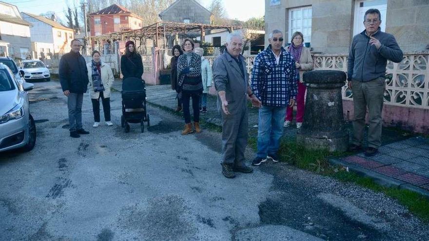 Algunos residentes en la calle Poza da Barcia muestran el avanzado deterioro del vial. // Rafa Vázquez