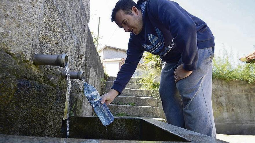 Un vecino recoge agua de una fuente, ayer en la parroquia de Mourente, Pontevedra. // Gustavo Santos