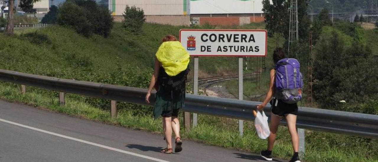 Dos peregrinas pasan al lado del cartel de Corvera de Asturias, en la entrada al concejo por Trasona desde Tabaza.