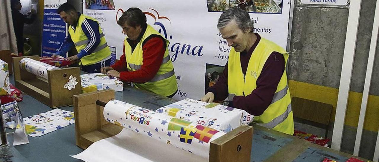 Tres voluntarios empaquetan juguetes. // Alba Villar