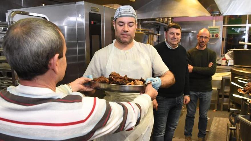 J.C., de espaldas. en los fogones de la Cocina Económica, como miembros de la entidad. | VÍCTOR ECHAVE