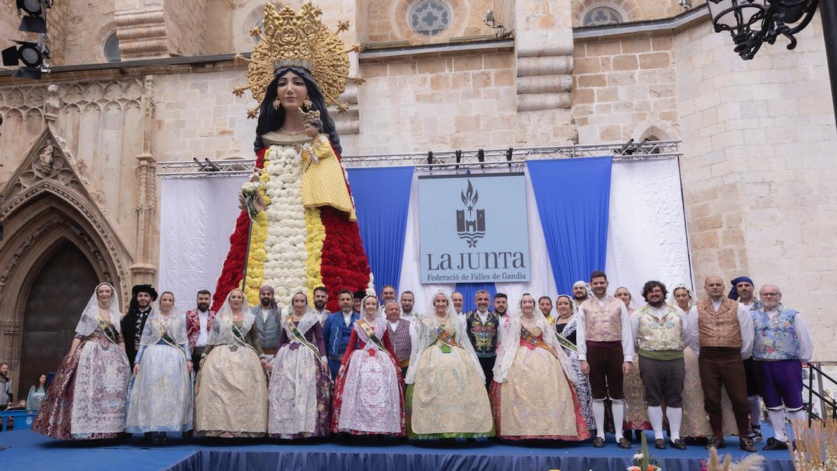 Las falleras mayores de Gandia, con representantes de la Junta y las autoridades locales, ante la imagen de la Mare de Déu repleta de flores.