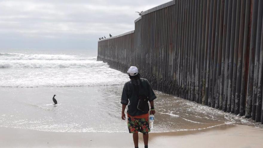 Migrante en el muro de separación entre EEUU y México.