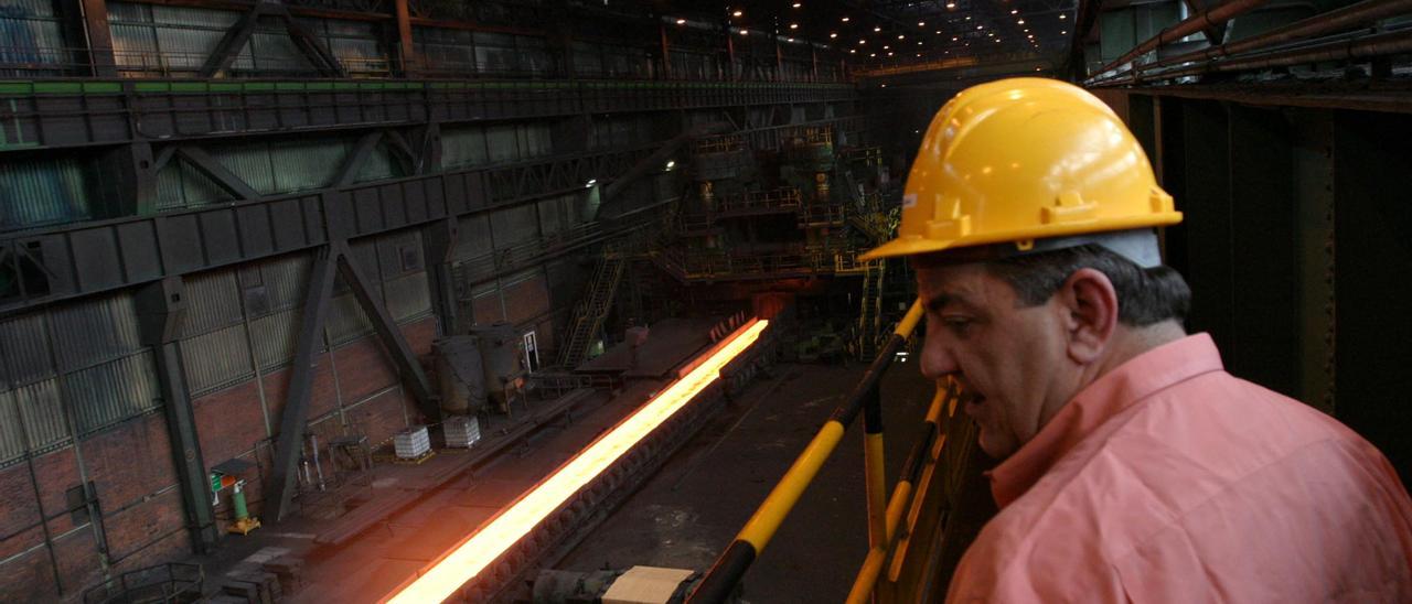 Un trabajador siderúrgico mira una pieza de acero candente.