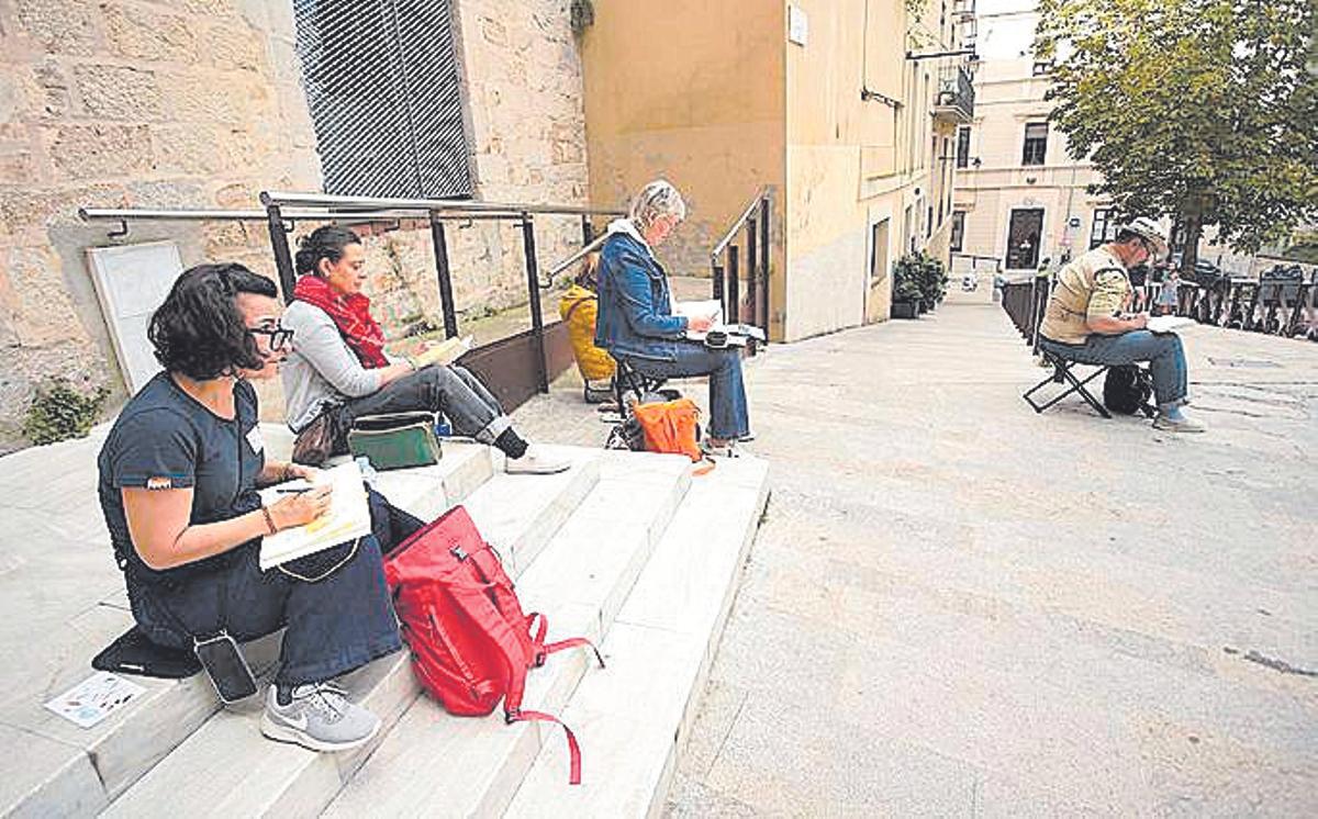 Un grup de persones davant de la Mercè fent els seus dibuixos.