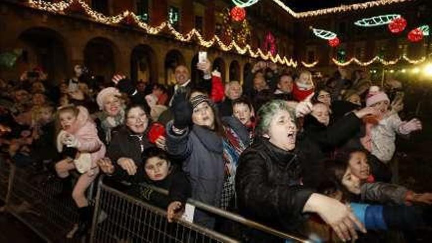 A la izquierda, niños y sus familias reclaman el saludo de los Reyes. A la derecha, Aliatar saluda a un niño en la plaza Mayor.