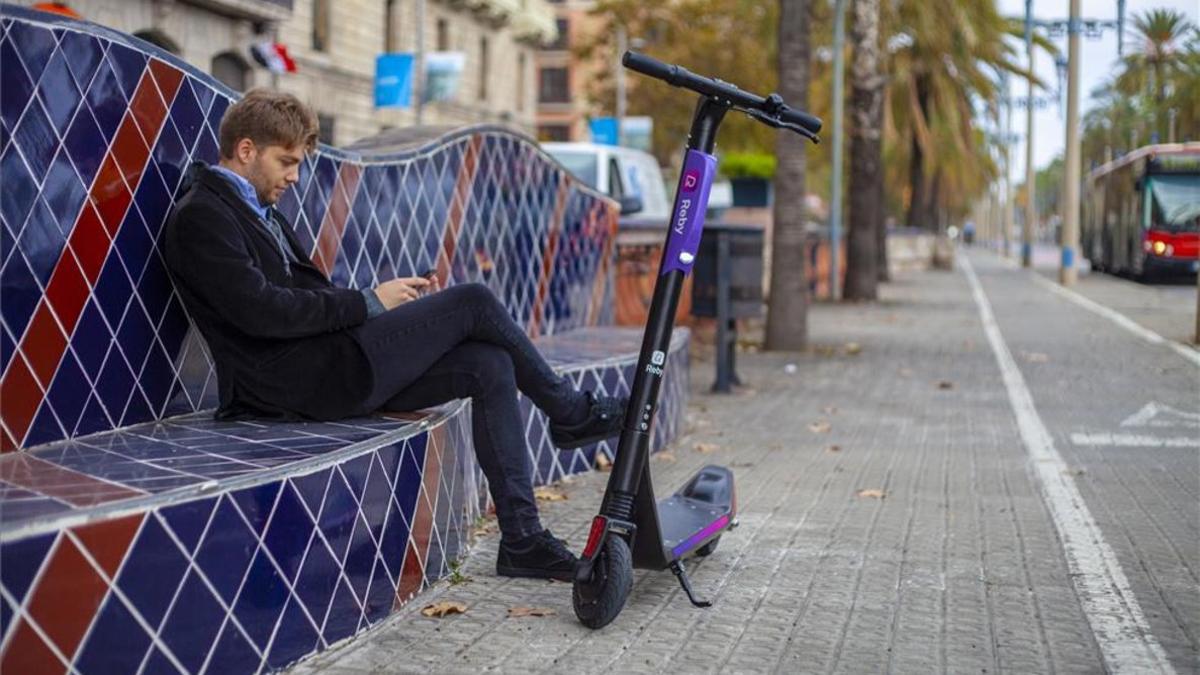 Un usuario y un patinete eléctrico Reby.