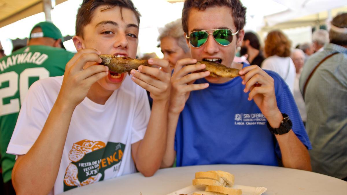 Dos asistentes al Día de la Tenca  devoran sendas piezas de pescado en una pasada edición.