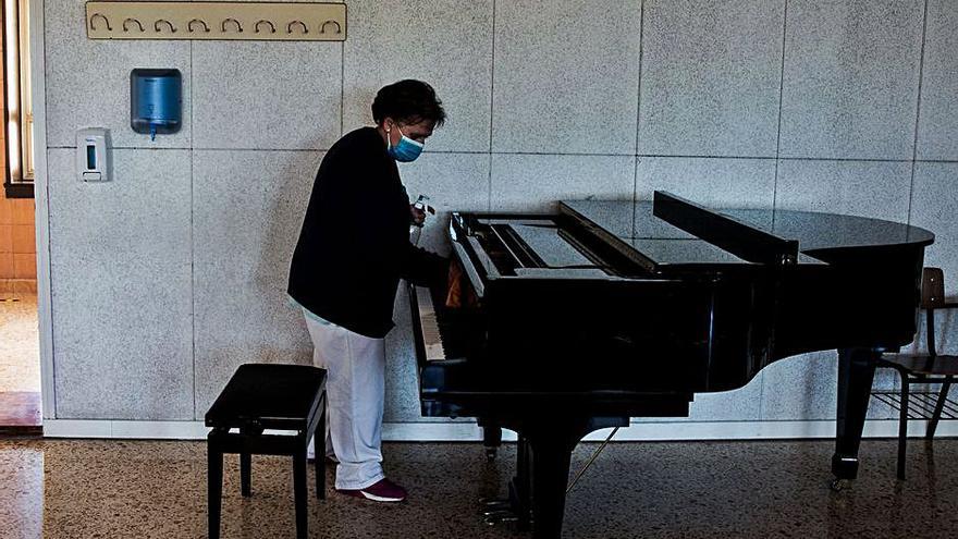 Una encargada de la limpieza, desinfecta el piano en una clase tras su uso.