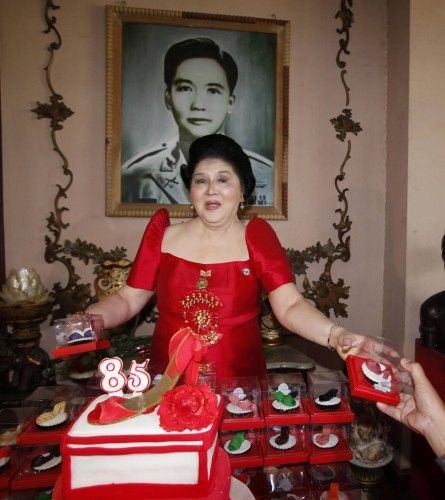 La ex primera dama de Filipinas y congresista Imelda Marcos da galletas a los partidarios de su difunto esposo, el ex presidente Ferdinand Marcos, bajo un retrato de Fernando en su hogar ancestral en su 85 cumpleaños, en Batac, en el norte de Filipin