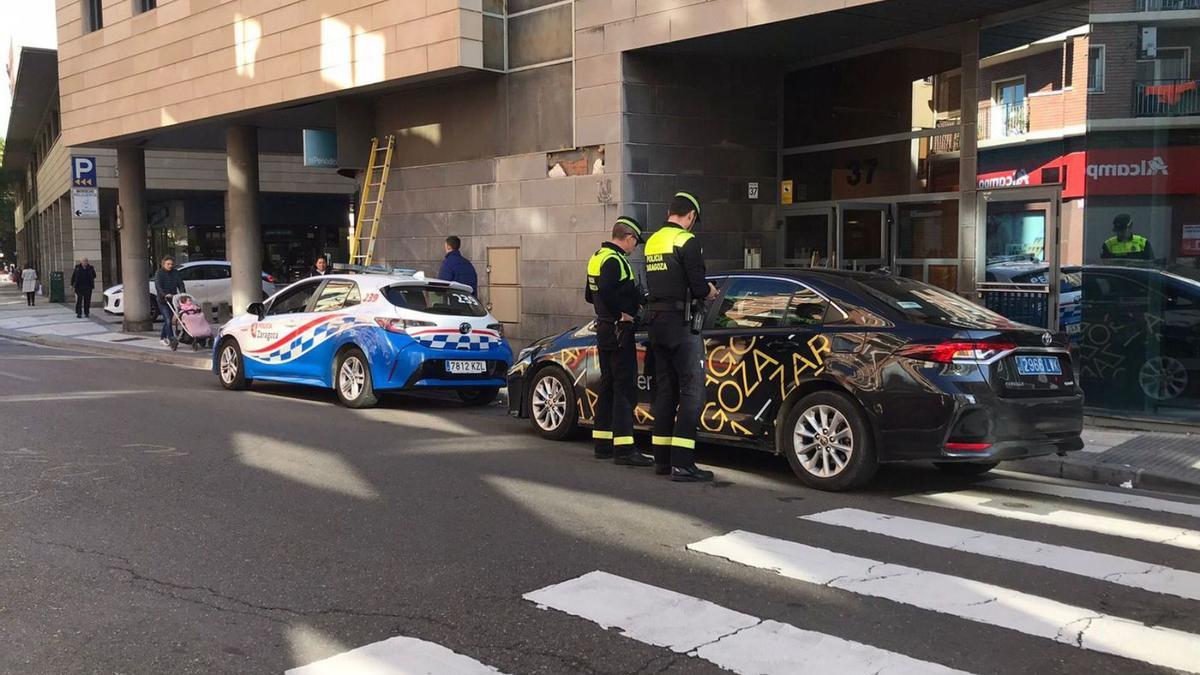 Dos agentes de la Policía Local de Zaragoza efectúan un control a un Uber, en la calle Cortes de Aragón, en una imagen de archivo.