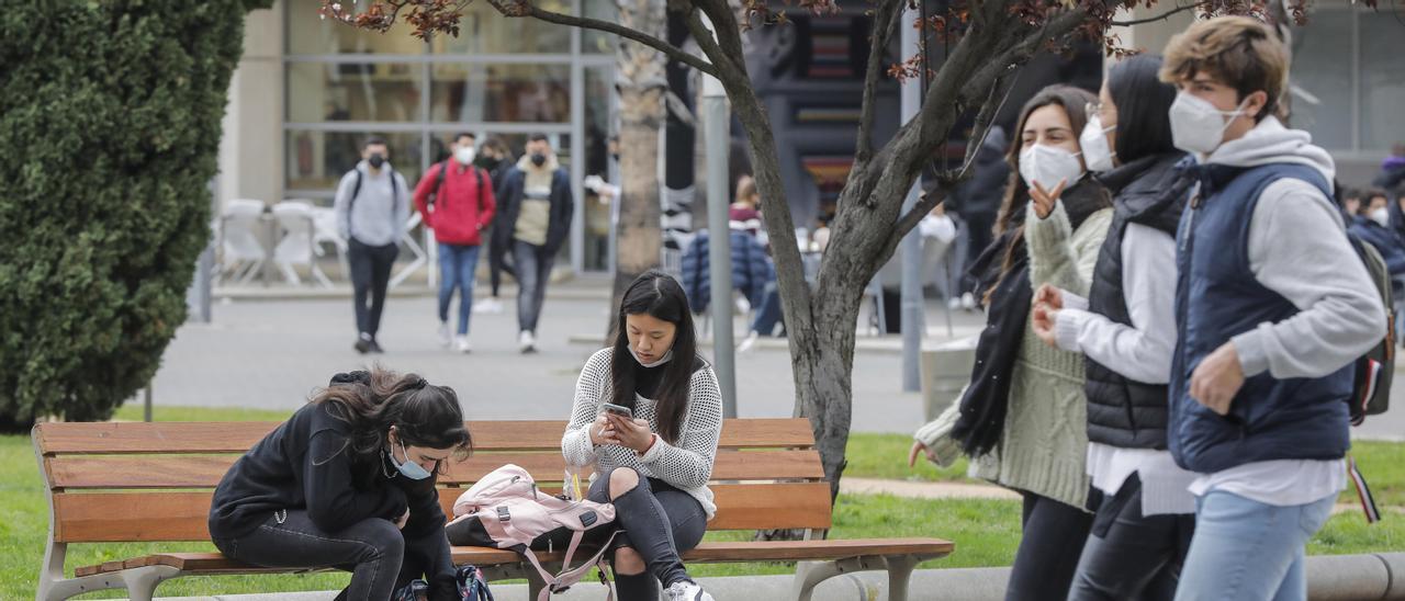 Varios universitarios pasean con mascarilla en Valencia.