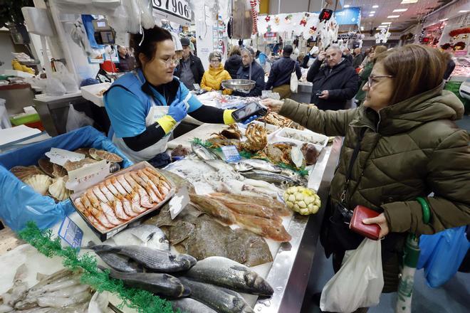 Una clienta paga con su tarjeta en un puesto de pescado