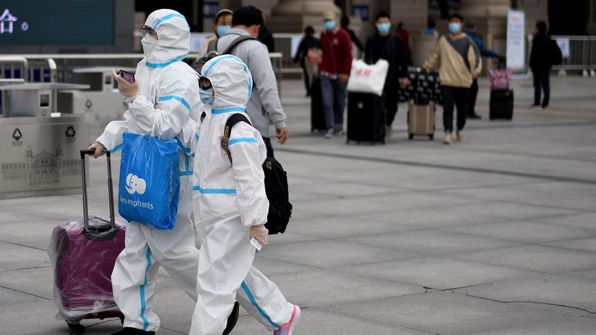 Pasajeros llegan a Wuhan protegidos con trajes.