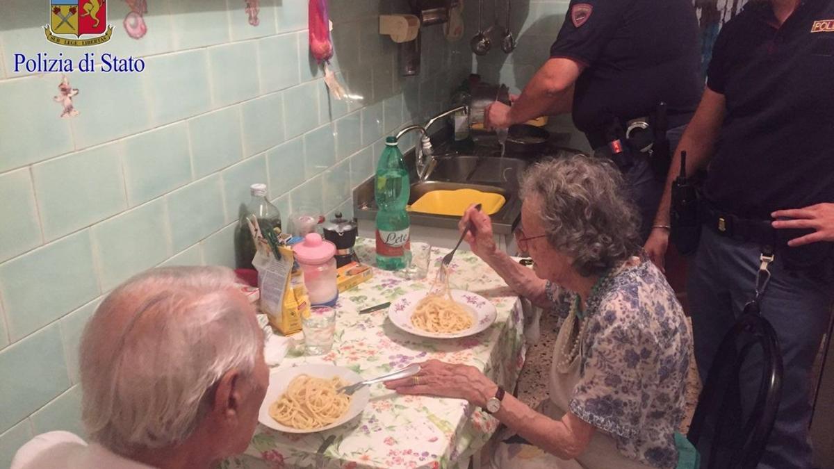 Michele, de espaldas, y Jole comen el plato de pasta que les han preparado los agentes de la policía de Roma.