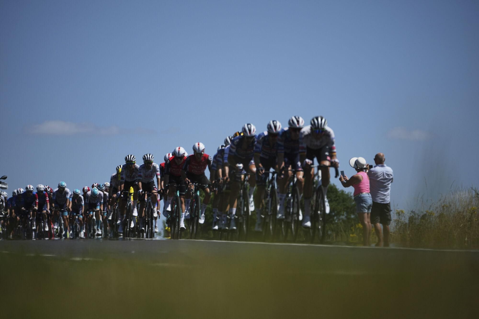 People take photos of the pack during the sixth stage of the Tour de France cycling race over 201.5 kilometers (125.2 miles) with start in Bayeux and finish in Vire Normandy, France, Thursday, July 10, 2025. (AP Photo/Thibault Camus)