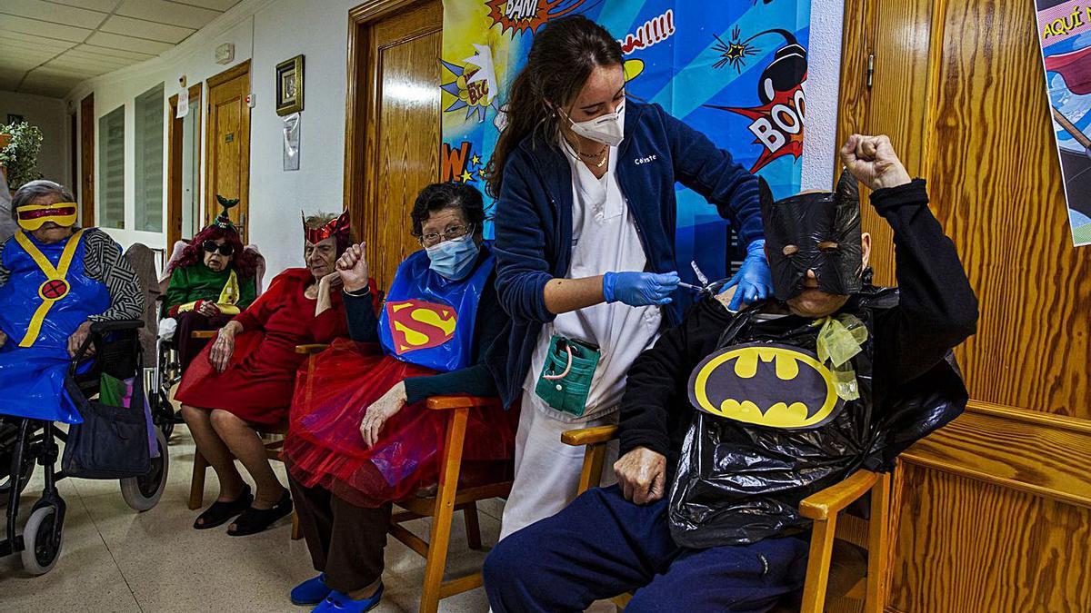 Otro usuario del geriátrico, disfrazado de Batman, recibe la segunda dosis de la vacuna.  | RAFA ARJONES